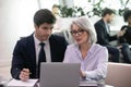 Mature businesswoman use laptop discussing business plan with younger colleague