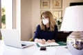Mature businesswoman wearing face mask and using laptop while working from home Royalty Free Stock Photo