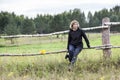 Mature calm woman with binocular in hand sitting on wooden fence of paddock, copy space Royalty Free Stock Photo