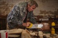 Mature carpenter sawing wood with a saw in his workshop for making wooden toys Royalty Free Stock Photo