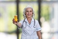 Mature caucasian female doctor showing a bottle of pills and smiling. Royalty Free Stock Photo