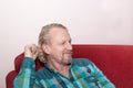 A mature Caucasian man with a beard is sitting on the couch, looking to the side and smiling. Positive portrait of a man Royalty Free Stock Photo