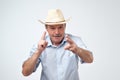 Mature caucasian man in cowboy hat making a sign with fingers like he is shooting ahead. Royalty Free Stock Photo