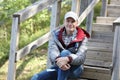 Mature traveler resting on wooden stairs of a tourist footpath outdoors