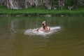 Mature caucasian man holding waterproof camera and swimming in river, trying to catch some interesting shots Royalty Free Stock Photo