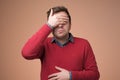 Man in red sweater covering eyes trying to stay away from problems. Royalty Free Stock Photo