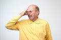 Mature caucasian man in yellow tshirtwith disgust on his face pinches nose. Royalty Free Stock Photo