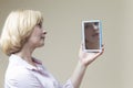 Mature Caucasian Woman Examining Her Face In Hand Mirror And Examining Skin Indoors Royalty Free Stock Photo