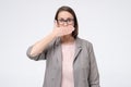 Mature caucasian woman in glasses covering mouth. I will not tell this secret anybody