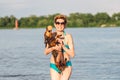 Mature caucasian woman plays ball in water with dog of Dachshund breed. Summertime theme with pet swim in river. Hot weather in Royalty Free Stock Photo