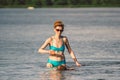 Mature caucasian woman plays ball in water with dog of Dachshund breed. Summertime theme with pet swim in river. Hot weather in Royalty Free Stock Photo