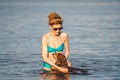 Mature caucasian woman plays ball in water with dog of Dachshund breed. Summertime theme with pet swim in river. Hot weather in Royalty Free Stock Photo