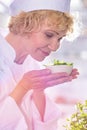 Mature chef smelling herbs on bowl in kitchen