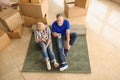 Mature couple with belongings sitting on carpet and drinking tea indoors. Moving into new house Royalty Free Stock Photo