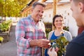 Mature Couple Buying Plants From Male Sales Assistant In Garden Center Royalty Free Stock Photo