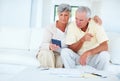 Mature couple calculating home budget. Mature couple calculating home budget while sitting on couch. Royalty Free Stock Photo