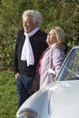 Mature couple by car in countryside, smiling, portrait