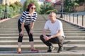 Mature couple in city near the stairs, middle-aged man and woman in sportswear talking resting after running