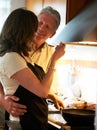 Mature couple, cooking together and hug with food, love and marriage, helping at stove in home. Meal prep, old man and Royalty Free Stock Photo