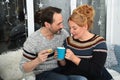Mature couple drinking coffee with cakes at home. Home, happy middle aged couple enjoying cup of coffee in warm winter