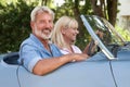 Portrait Of Mature Couple Enjoying Road Trip In Classic Open Top Sports Car Together