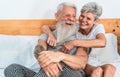 Mature couple enjoying time together at home after waking up - Senior man and woman having tender moments sitting in bed - Love Royalty Free Stock Photo