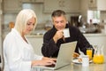 Mature couple having breakfast together woman using laptop Royalty Free Stock Photo