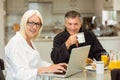 Mature couple having breakfast together woman using laptop Royalty Free Stock Photo