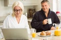 Mature couple having breakfast together woman using laptop Royalty Free Stock Photo