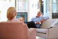 Mature Couple At Home Relaxing In Lounge With Hot Drink Royalty Free Stock Photo