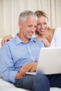 Mature couple, laptop and watching with laugh, conversation and living room couch. Social media, technology and Royalty Free Stock Photo