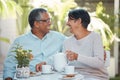 Mature couple laughing, drinking tea and bonding in backyard together, relax and cheerful outdoors. Senior man and woman Royalty Free Stock Photo
