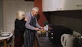 Mature couple in love making dinner. Elderly woman hugging from back husband cooking meal in kitchen Royalty Free Stock Photo