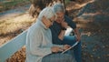 Mature couple in love taking selfie in forest on autumn day. Video call or browsing old photos Royalty Free Stock Photo