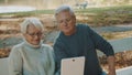 Mature couple in love taking selfie in forest on autumn day. Video call or browsing old photos Royalty Free Stock Photo