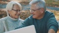 Mature couple in love taking selfie in forest on autumn day. Video call or browsing old photos Royalty Free Stock Photo