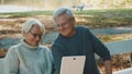 Mature couple in love taking selfie in forest on autumn day. Video call or browsing old photos Royalty Free Stock Photo