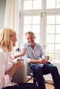 Mature Couple With Man In Wheelchair Sitting In Lounge At Home Talking Together Royalty Free Stock Photo