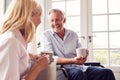 Mature Couple With Man In Wheelchair Sitting In Lounge At Home Talking Together Royalty Free Stock Photo