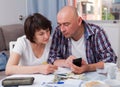 Mature couple with phone calculation money sitting at table Royalty Free Stock Photo