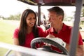 Mature Couple Playing Golf Marking Scorecard In Buggy Driving Along Course Royalty Free Stock Photo