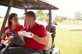 Mature Couple Playing Golf Marking Scorecard In Buggy Driving Along Course Royalty Free Stock Photo