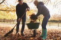 Mature Couple Raking Autumn Leaves in Garden Royalty Free Stock Photo