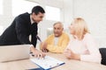 Mature couple at a reception with a lawyer. The lawyer puts a seal on the contract, the old people are happy about this.