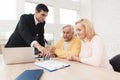 Mature couple at a reception with a lawyer. The lawyer puts a seal on the contract, the old people are happy about this.