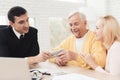 Mature couple at a reception with a lawyer. The old man and the lawyer are holding a bundle of money. Royalty Free Stock Photo