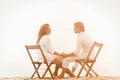 Mature couple resting at beach holding hands. Happy man and woman holding hands and looking each other while sitting on Royalty Free Stock Photo