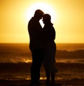 Mature couple resting their heads together. Silhouette of senior couple bonding on the beach. Married senior couple