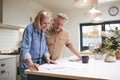 Mature Couple Reviewing Domestic Finances And Investments In Kitchen At Home Together Royalty Free Stock Photo