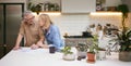 Mature Couple Reviewing And Signing Domestic Finances And Investment Paperwork In Kitchen At Home Royalty Free Stock Photo